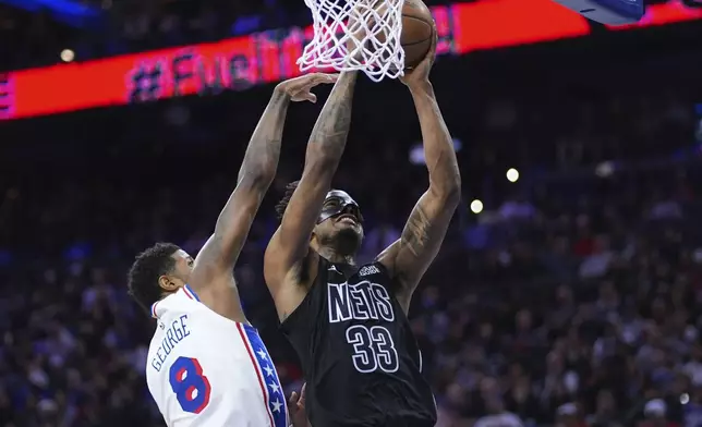 Brooklyn Nets' Nic Claxton, right, goes up for a shot against Philadelphia 76ers' Paul George during the first half of an NBA basketball game, Saturday, Feb. 22, 2025, in Philadelphia. (AP Photo/Matt Slocum)