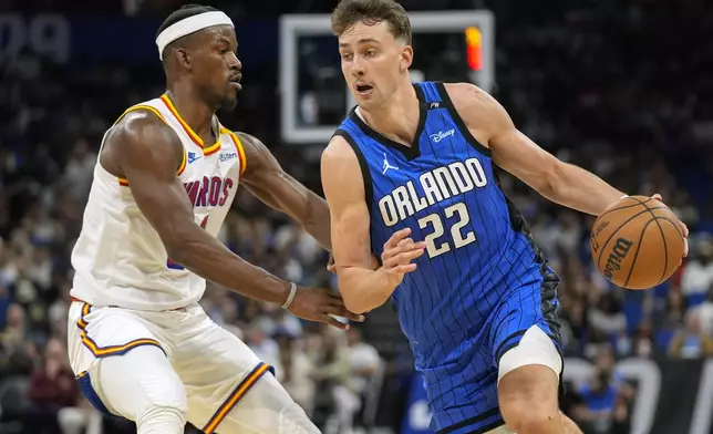 Orlando Magic forward Franz Wagner (22) drives past Golden State Warriors forward Jimmy Butler, left, during the first half of an NBA basketball game, Thursday, Feb. 27, 2025, in Orlando, Fla. (AP Photo/John Raoux)