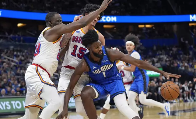 Orlando Magic forward Jonathan Isaac (1) loses control of the ball as his path to the basket is blocked by Golden State Warriors forward Draymond Green, left, and forward Gui Santos (15) during the first half of an NBA basketball game, Thursday, Feb. 27, 2025, in Orlando, Fla. (AP Photo/John Raoux)