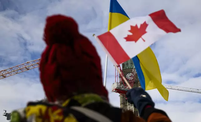 People wave the Canadian and Ukrainian flags as they rally on Parliament Hill to mark the 3rd anniversary of Russia's full-scale invasion of Ukraine, in Ottawa, on Sunday, Feb. 23, 2025. (Justin Tang/The Canadian Press via AP)