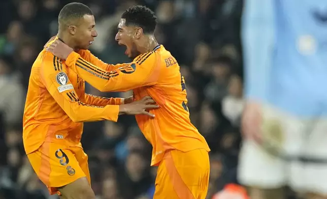 Real Madrid's Kylian Mbappe, left, celebrates with Real Madrid's Jude Bellingham after socring his sides first goal during the Champions League playoff first leg soccer match between Manchester City and Real Madrid at the Etihad Stadium in Manchester, England, Tuesday, Feb. 11, 2025. (AP Photo/Dave Thompson)