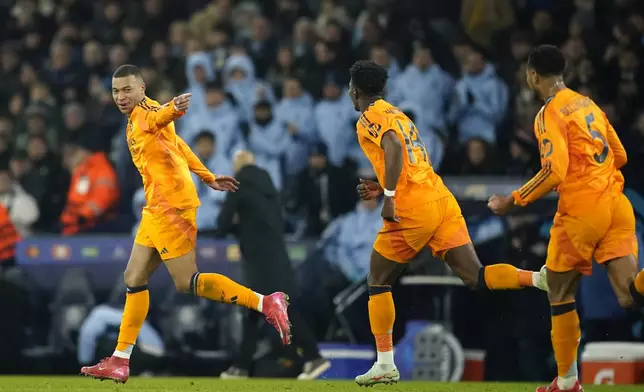 Real Madrid's Kylian Mbappe, left, runs to celebrate after socring his sides first goal during the Champions League playoff first leg soccer match between Manchester City and Real Madrid at the Etihad Stadium in Manchester, England, Tuesday, Feb. 11, 2025. (AP Photo/Dave Thompson)