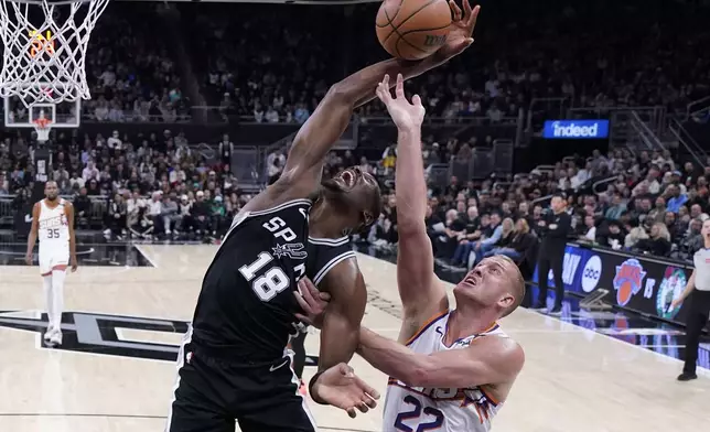 San Antonio Spurs center Bismack Biyombo (18) and Phoenix Suns center Mason Plumlee (22) reach for a rebound during the second half of an NBA basketball game in Austin, Texas, Thursday, Feb. 20, 2025. (AP Photo/Eric Gay)