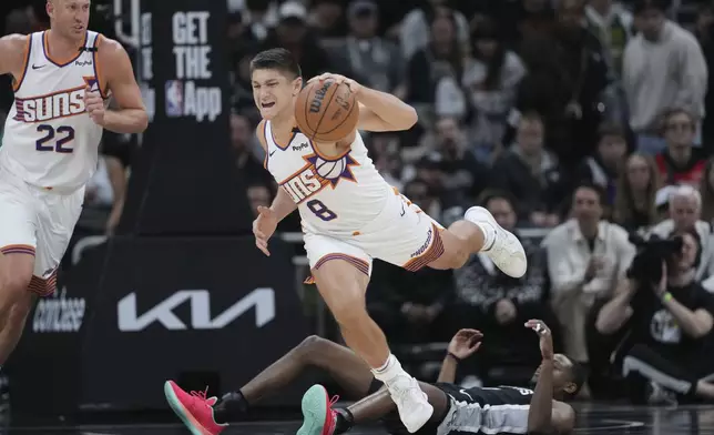 Phoenix Suns guard Grayson Allen (8) is tripped up as he and San Antonio Spurs guard De'Aaron Fox, right, chase a loose ball during the second half of an NBA basketball game in Austin, Texas, Thursday, Feb. 20, 2025. (AP Photo/Eric Gay)