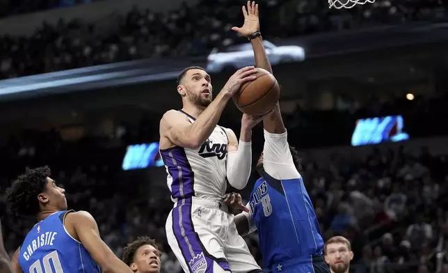 Sacramento Kings guard Mason Jones, center, leaps to the basket for a shot as Dallas Mavericks' Max Christie (00) and Olivier-Maxence Prosper (8) defend in the first half of an NBA basketball game in Dallas, Monday, Feb. 10, 2025. (AP Photo/Tony Gutierrez)