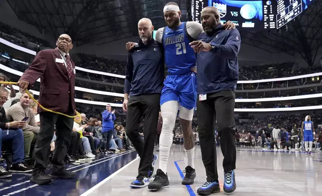 Dallas Mavericks center Daniel Gafford (21) is assisted off the court by team staff after suffering an unknown injury in the first half of an NBA basketball game against the Sacramento Kings in Dallas, Monday, Feb. 10, 2025. (AP Photo/Tony Gutierrez)
