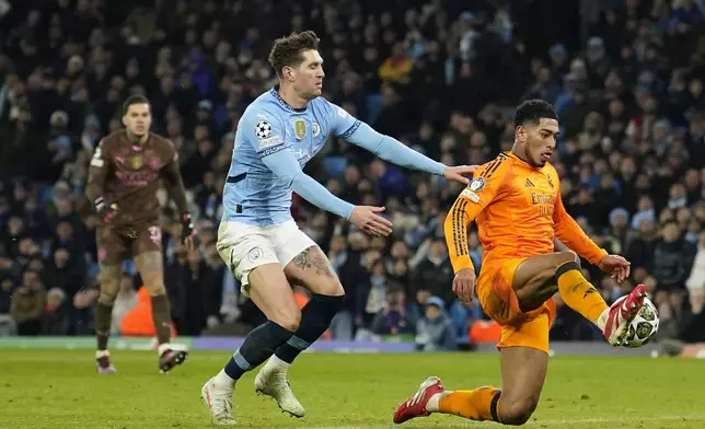 Real Madrid's Jude Bellingham, right, scores his sides third goal during the Champions League playoff first leg soccer match between Manchester City and Real Madrid at the Etihad Stadium in Manchester, England, Tuesday, Feb. 11, 2025. (AP Photo/Dave Thompson)