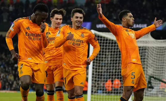 Real Madrid's Jude Bellingham, right, celebrates with teammates after scoring his sides third goal during the Champions League playoff first leg soccer match between Manchester City and Real Madrid at the Etihad Stadium in Manchester, England, Tuesday, Feb. 11, 2025. (AP Photo/Dave Thompson)