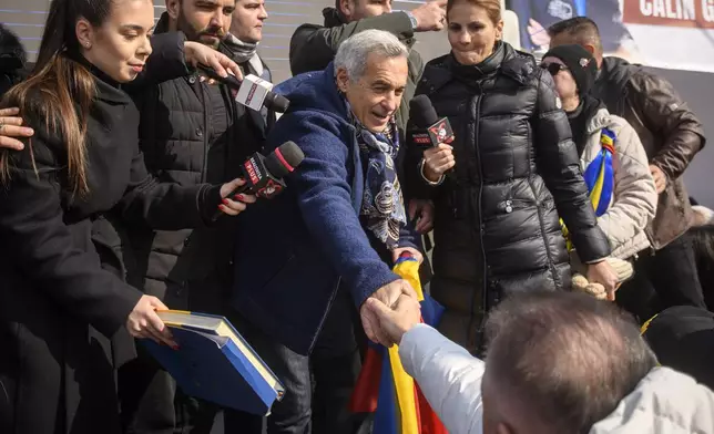 Calin Georgescu, the winner of Romania's first round of presidential election, annulled by the Constitutional Court, shakes hands with one of the thousands of supporters gathered for a protest outside the Romanian parliament in Bucharest, Romania, Saturday, Feb. 22, 2025. (AP Photo/Alexandru Dobre)