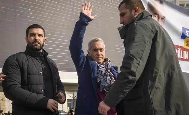 Calin Georgescu, the winner of Romania's first round of presidential election, annulled by the Constitutional Court, waves to supporters gathered for a protest outside the Romanian parliament in Bucharest, Romania, Saturday, Feb. 22, 2025. (AP Photo/Alexandru Dobre)