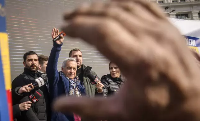 Calin Georgescu, the winner of Romania's first round of presidential election, annulled by the Constitutional Court, waves to supporters gathered for a protest outside the Romanian parliament in Bucharest, Romania, Saturday, Feb. 22, 2025. (AP Photo/Alexandru Dobre)