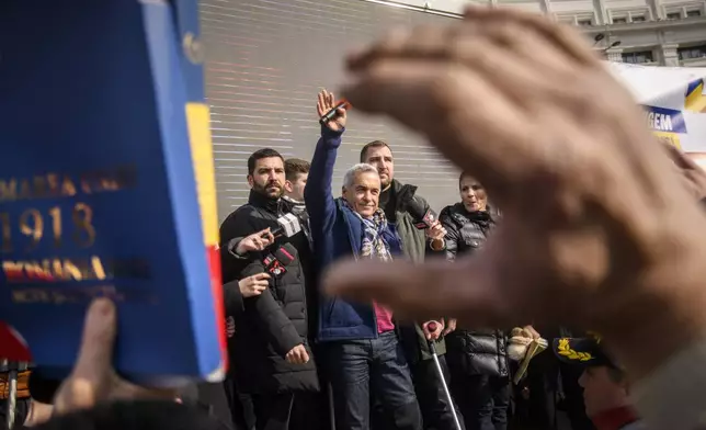 Calin Georgescu, the winner of Romania's first round of presidential election, annulled by the Constitutional Court, waves to supporters gathered for a protest outside the Romanian parliament in Bucharest, Romania, Saturday, Feb. 22, 2025. (AP Photo/Alexandru Dobre)