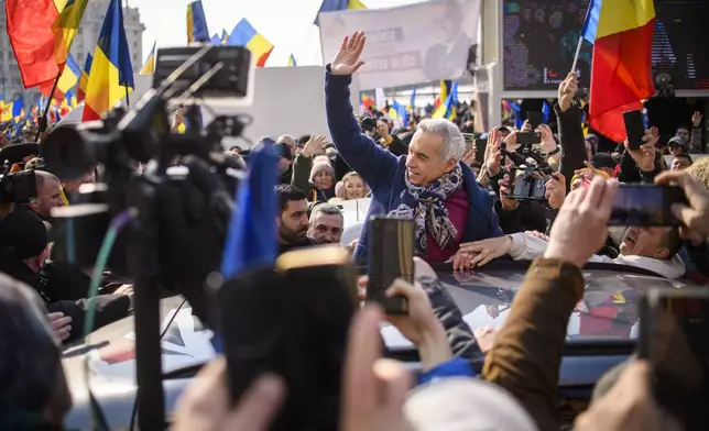 Calin Georgescu, the winner of Romania's first round of presidential election, annulled by the Constitutional Court, waves to supporters gathered for a protest outside the Romanian parliament in Bucharest, Romania, Saturday, Feb. 22, 2025. (AP Photo/Alexandru Dobre)