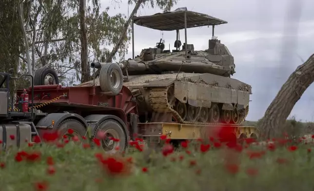 An Israeli tank is loaded onto a transport truck near the border with the Gaza Strip in southern Israel, Sunday, Feb. 9, 2025. (AP Photo/Ohad Zwigenberg)