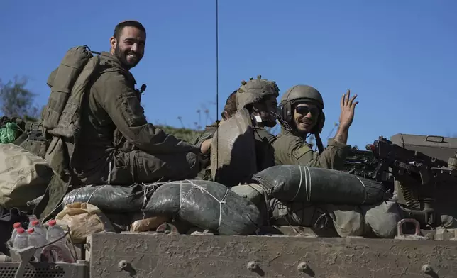 FILE - Israeli soldiers wave to the camera from an APC as they cross from the Gaza Strip into Israel, Saturday, Jan. 18, 2025. (AP Photo/Tsafrir Abayov, File)