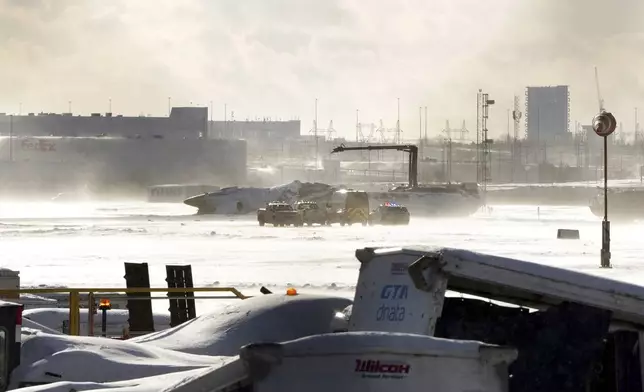 Emergency response vehicles are seen nearby an upside down Delta Air Lines plane, which was heading from Minneapolis to Toronto when it crashed on the runway at Pearson International Airport, in Toronto, Monday, Feb. 17, 2025. (Teresa Barbieri/The Canadian Press via AP)