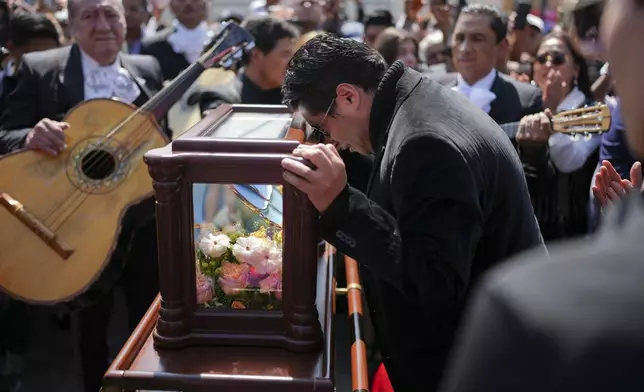 A friend grieves as he rests his head on a case holding the remains of Mexican musical legend Paquita la del Barrio during a memorial tribute at Plaza Garibaldi, in Mexico City, Friday, Feb. 21, 2025. (AP Photo/Eduardo Verdugo)