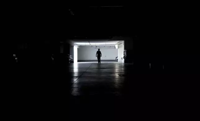A man walks in a parking garage during a power outage, in Santiago, Chile, Tuesday, Feb. 25, 2025. (AP Photo/Matias Basualdo)