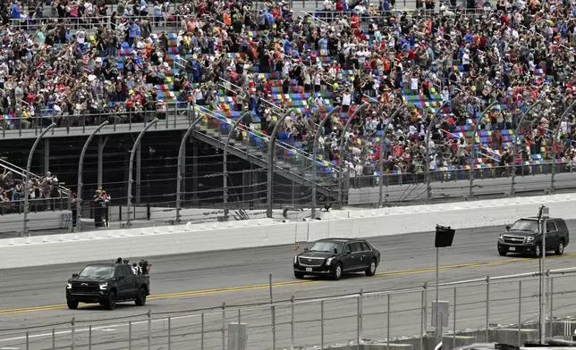 President Donald Trump, center, in the presidential limousine known as "The Beast" does a lap around the track at the NASCAR Daytona 500 auto race at Daytona International Speedway, Sunday, Feb. 16, 2025, in Daytona Beach, Fla. (Pool via AP)