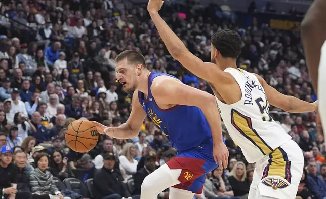 Denver Nuggets center Nikola Jokic, left, drives to the basket as New Orleans Pelicans forward Jeremiah Robinson-Earl, right, defends in the first half of an NBA basketball game Monday, Feb. 3, 2025, in Denver. (AP Photo/David Zalubowski)