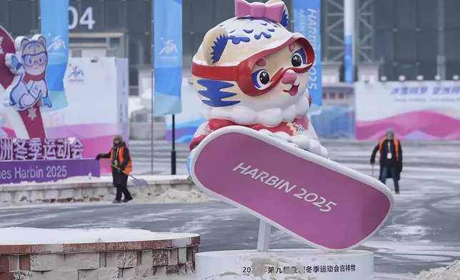 Workers try to clear an area with snow ahead of the 9th Asian Winter Games in Harbin, China on Friday, Feb. 7, 2025. (AP Photo/Aaron Favila)