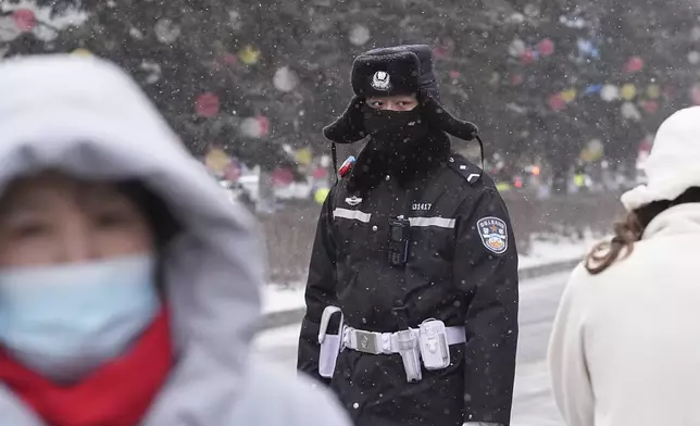 A policeman watches as snow falls ahead of the 9th Asian Winter Games in Harbin, China on Friday, Feb. 7, 2025. (AP Photo/Aaron Favila)