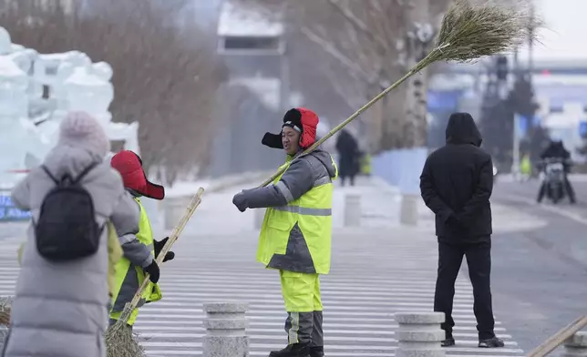 A worker talks after clearing an area of snow ahead of the 9th Asian Winter Games in Harbin, China on Friday, Feb. 7, 2025. (AP Photo/Aaron Favila)