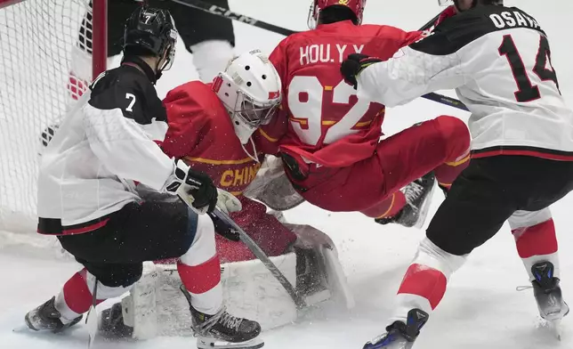 China's goalkeeper Chen Shifeng, second from left, defends the goal against Japan players at the Ice Hockey during the 9th Asian Winter Games in Harbin, China on Monday, Feb. 10, 2025. (AP Photo/Aaron Favila)