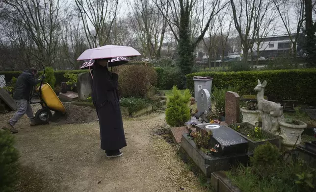 Tourists visit the dog cemetery while a worker prepares a tomb in Asnières-sur-Seine, outside Paris, Tuesday, Feb. 25, 2025. (AP Photo/Christophe Ena)
