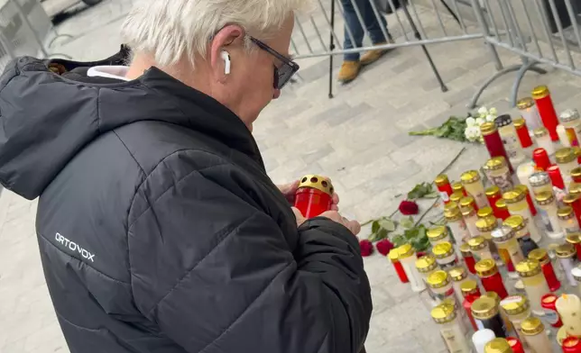 A man lights a candle at the site of stabbing a day after an attack that left a 14-year-old dead and five others injured, in Villach, Austria, Sunday, Feb. 16, 2025. (AP Photo/Darko Bandic)