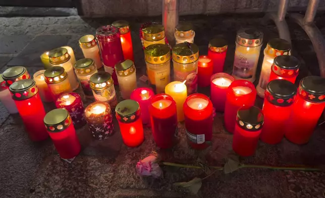 Candles are lit at the site of a stabbing attack in Villach, Austria, Sunday, Feb. 16, 2025. (AP Photo/Darko Bandic)