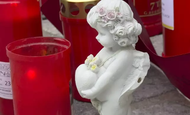 A figurine of angel is placed with candles at the site of stabbing a day after an attack that left a 14-year-old dead and five others injured, in Villach, Austria, Sunday, Feb. 16, 2025. (AP Photo/Darko Bandic)