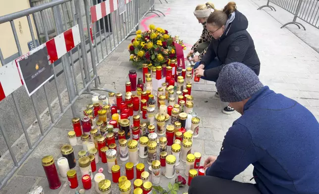 People light candles at the site of stabbing a day after an attack that left a 14-year-old dead and five others injured, in Villach, Austria, Sunday, Feb. 16, 2025. (AP Photo/Darko Bandic)
