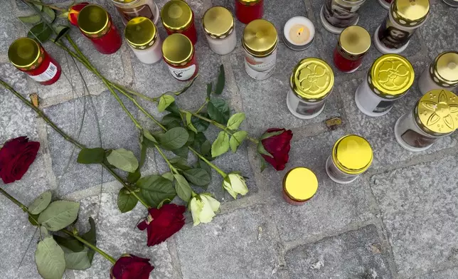 Candles and flowers are placed at the site of stabbing a day after an attack that left a 14-year-old dead and five others injured, in Villach, Austria, Sunday, Feb. 16, 2025. (AP Photo/Darko Bandic)