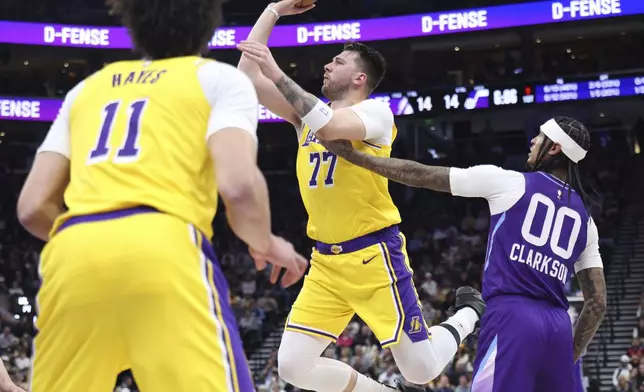 Los Angeles Lakers guard Luka Doncic (77) shoots as Utah Jazz guard Jordan Clarkson (00) defends during the first half of an NBA basketball game, Wednesday, Feb. 12, 2025, in Salt Lake City. (AP Photo/Rob Gray)