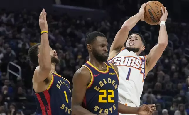 Phoenix Suns guard Devin Booker, right, shoots against Golden State Warriors forward Kyle Anderson, left, and forward Andrew Wiggins during the first half of an NBA basketball game in San Francisco, Friday, Jan. 31, 2025. (AP Photo/Jeff Chiu)
