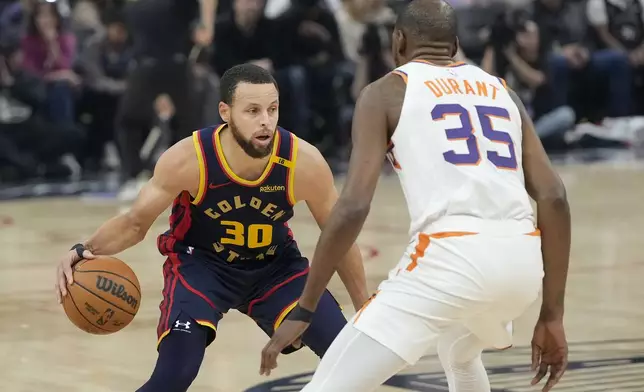 Golden State Warriors guard Stephen Curry (30) dribbles while being defended by Phoenix Suns forward Kevin Durant (35) during the first half of an NBA basketball game in San Francisco, Friday, Jan. 31, 2025. (AP Photo/Jeff Chiu)