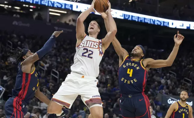 Phoenix Suns center Mason Plumlee (22) shoots against Golden State Warriors forward Kevon Looney, left, and guard Moses Moody (4) during the first half of an NBA basketball game in San Francisco, Friday, Jan. 31, 2025. (AP Photo/Jeff Chiu)