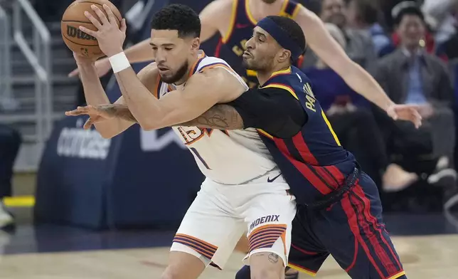 Golden State Warriors guard Gary Payton II, right, reaches for the ball while defending Phoenix Suns guard Devin Booker during the first half of an NBA basketball game in San Francisco, Friday, Jan. 31, 2025. (AP Photo/Jeff Chiu)