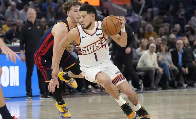 Phoenix Suns guard Devin Booker (1) drives to the basket against Golden State Warriors guard Brandin Podziemski during the first half of an NBA basketball game in San Francisco, Friday, Jan. 31, 2025. (AP Photo/Jeff Chiu)