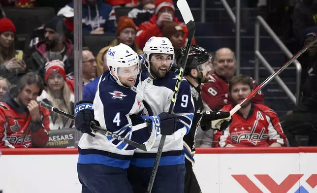 Winnipeg Jets left wing Alex Iafallo (9) celebrates his goal with defenseman Neal Pionk (4) during the second period of an NHL hockey game against the Washington Capitals, Saturday, Feb. 1, 2025, in Washington. (AP Photo/Nick Wass)