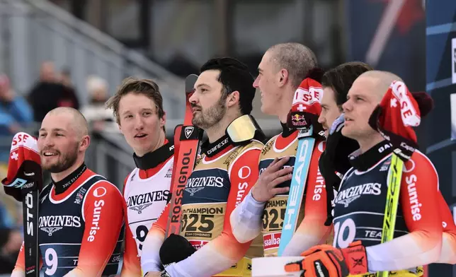 Switzerland's Loic Meillard, third from left, and teammate Franjo von Allmen, third from right, celebrate on the podium after winning the gold medal in a men's team combined event, with silver medalists Switzerland's Alexis Monney, left, and teammate Nef Tanguy, and and bronze medalists Switzerland's Marc Rochat, second from right, and teammate Stefan Rogentin, at the Alpine Ski World Championships, in Saalbach-Hinterglemm, Austria, Wednesday, Feb. 12, 2025. (AP Photo/Marco Trovati)
