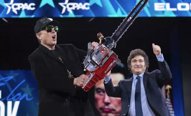 Elon Musk, left, receives a chainsaw from Argentina's President Javier Milei as they arrive speaks at the Conservative Political Action Conference, CPAC, at the Gaylord National Resort &amp; Convention Center, Thursday, Feb. 20, 2025, in Oxon Hill, Md. (AP Photo/Jose Luis Magana)