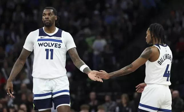Minnesota Timberwolves center Naz Reid (11) and guard Rob Dillingham (4) slap hands during the first half of an NBA basketball game against the Portland Trail Blazers, Saturday, Feb. 8, 2025, in Minneapolis. (AP Photo/Ellen Schmidt)