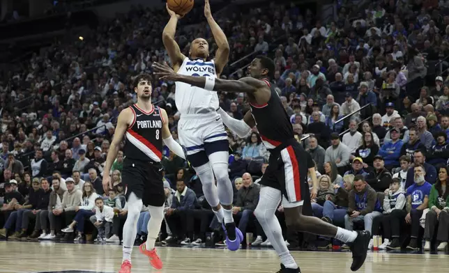Minnesota Timberwolves guard Terrence Shannon Jr. (00) shoots between Portland Trail Blazers forward Deni Avdija (8) and center Deandre Ayton, right, during the first half of an NBA basketball game, Saturday, Feb. 8, 2025, in Minneapolis. (AP Photo/Ellen Schmidt)