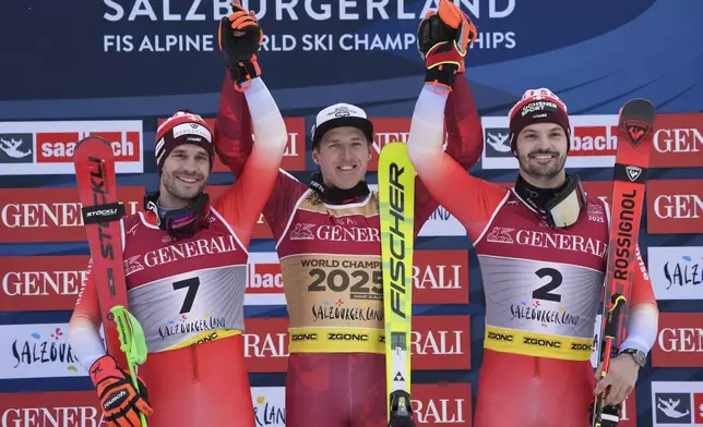 Austria's Raphael Haaser, center, winner of a gold medal in a men's giant slalom, celebrates on the podium with silver medalist Switzerland's Thomas Tumler, left, and bronze medalist Switzerland's Loic Meillard, at the Alpine Ski World Championships, in Saalbach-Hinterglemm, Austria, Friday, Feb. 14, 2025. (AP Photo/Giovanni Auletta)