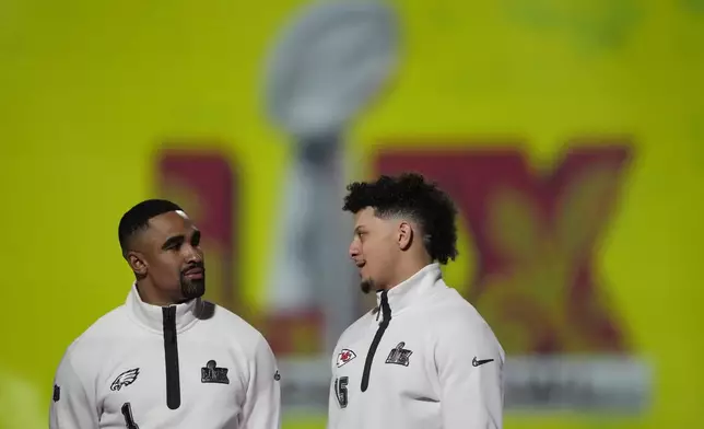 Philadelphia Eagles quarterback Jalen Hurts (1) and Kansas City Chiefs quarterback Patrick Mahomes (15) pose with the trophy during Super Bowl 59 Opening Night, Monday, Feb. 3, 2025, in New Orleans, ahead of the NFL football game between the Philadelphia Eagles and the Kansas City Chiefs Sunday. (AP Photo/Matt York)
