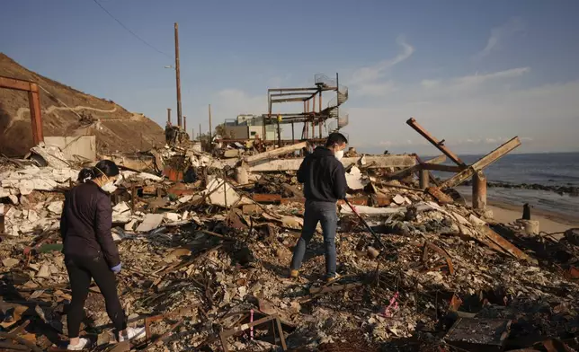 FILE - Tony Lai, center, rakes through the remains of his fire-ravaged beachfront property with his wife Everlyn in the aftermath of the Palisades Fire Tuesday, Jan. 28, 2025 in Malibu, Calif. (AP Photo/Jae C. Hong, File)