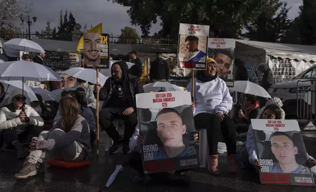 Activists sit on a road with white umbrellas during a protest calling for the release of hostages held in the Gaza Strip, outside the prime minister's house in Jerusalem, Wednesday, Feb. 12, 2025. (AP Photo/Ohad Zwigenberg)
