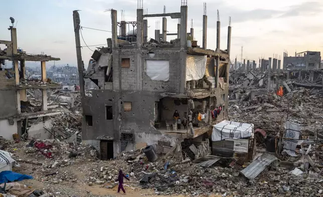 Palestinians stand in their partially standing homes, covered with sheets as makeshift walls, in an area largely destroyed by the Israeli army's air and ground offensive in Jabaliya, Gaza Strip, on Tuesday, Feb. 11, 2025. (AP Photo/Jehad Alshrafi)